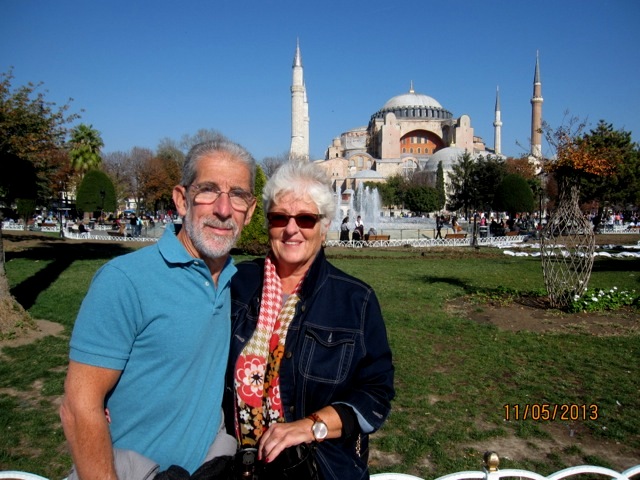 man and woman on green in front of istanbul domed building