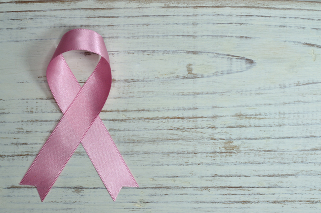grey wood background with pink ribbon folded over for cancer awareness