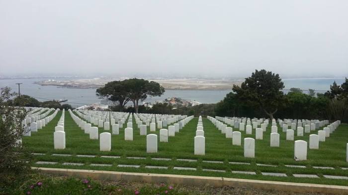 rows of white grave stones overlooking san diego naval base and the ocean