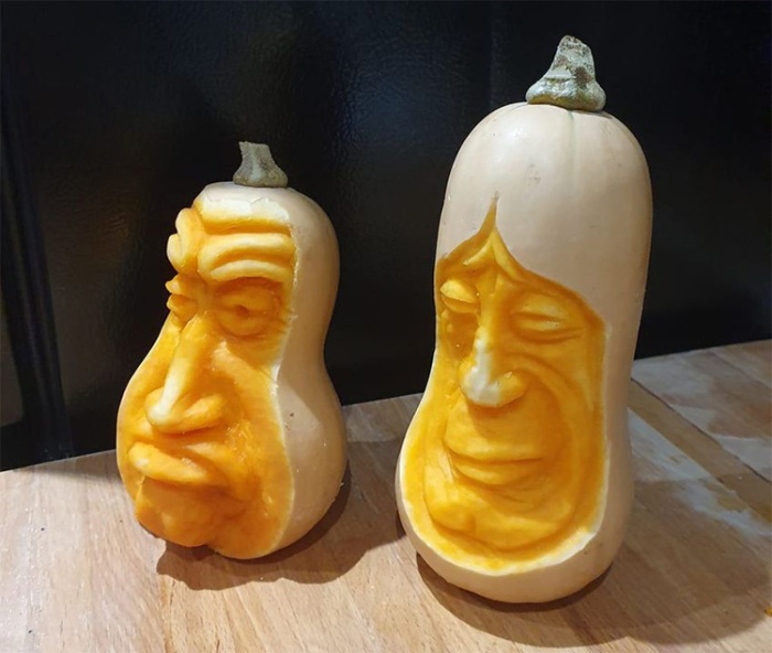 2 tall squash pumpkins with grumpy faces carved into the front.