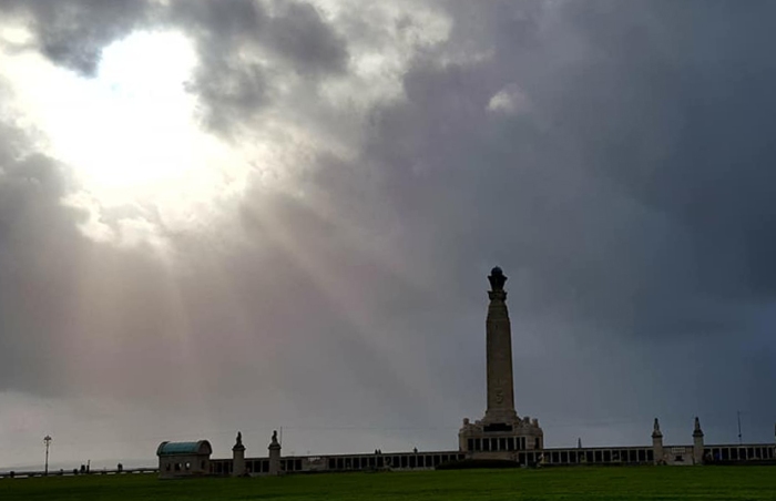 Dark stormy sky with sun breaking through the clouds over the epitaph at Southsea